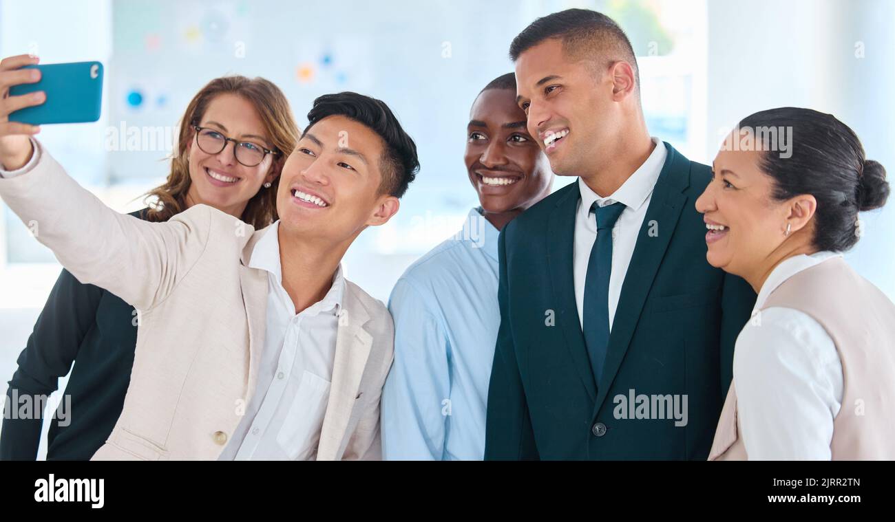Glückliche Geschäftsleute oder Freunde, die im Büro ein Selfie machen, mit der Arbeit und dem gemeinsamen Arbeiten. Mitarbeiterteam oder Gruppe von Kollegen, die ein nehmen Stockfoto