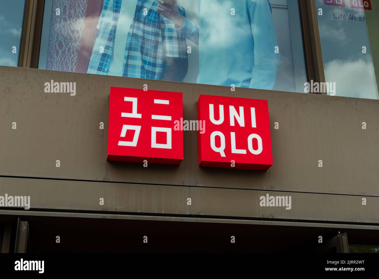 Uniqlo japanisches Modelabel auf einer Ladenfassade. Logo der Bekleidungsmarke auf der Außenseite eines Gebäudes. Werbung mit einem beleuchteten Markenemblem. Stockfoto