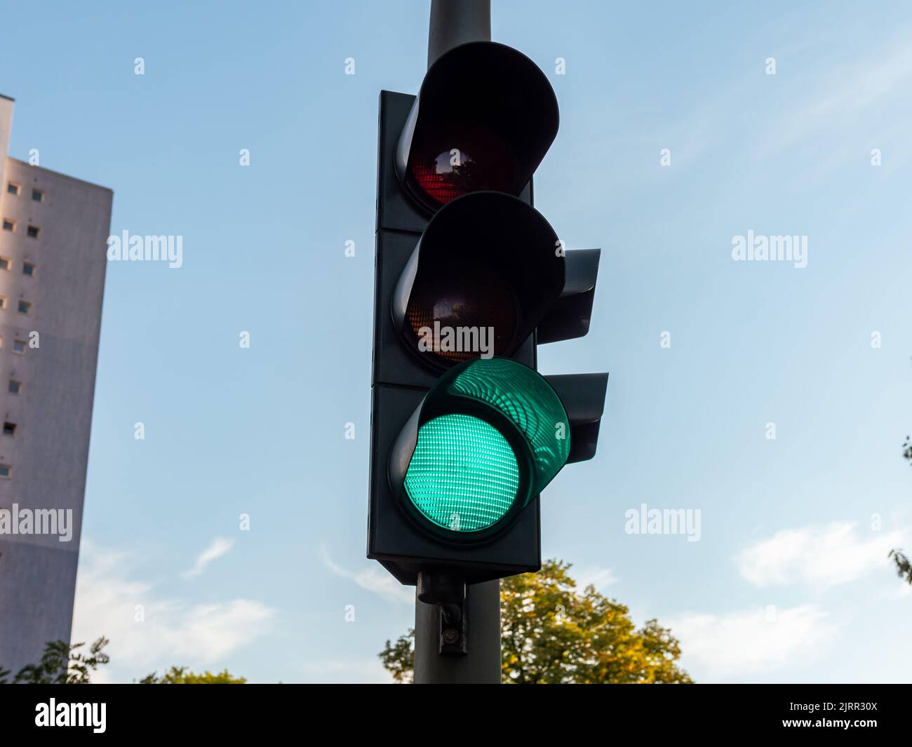 Grün leuchtende Ampel für Autofahrer. Dieses Lichtsignal neben der Straße zeigt an, dass der Verkehr weiterfahren kann. Sicherheit auf deutschen Straßen. Stockfoto