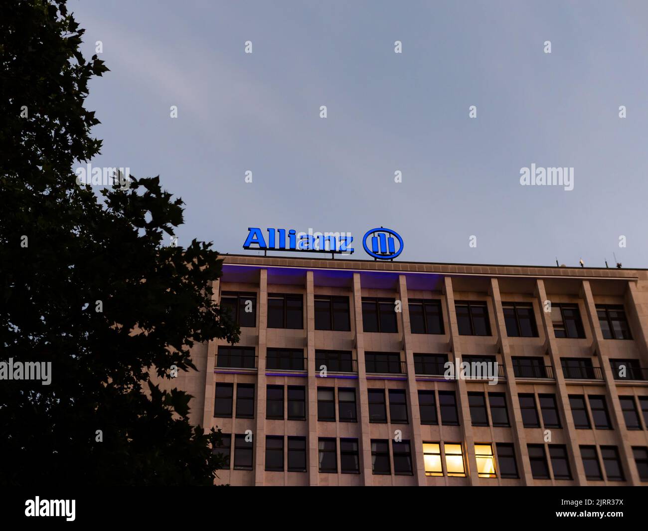 Allianz Finanzdienstleister in der Innenstadt. Bürogebäude mit einem beleuchteten Schild auf dem Dach. Geschäftsarchitektur für die Versicherung Stockfoto