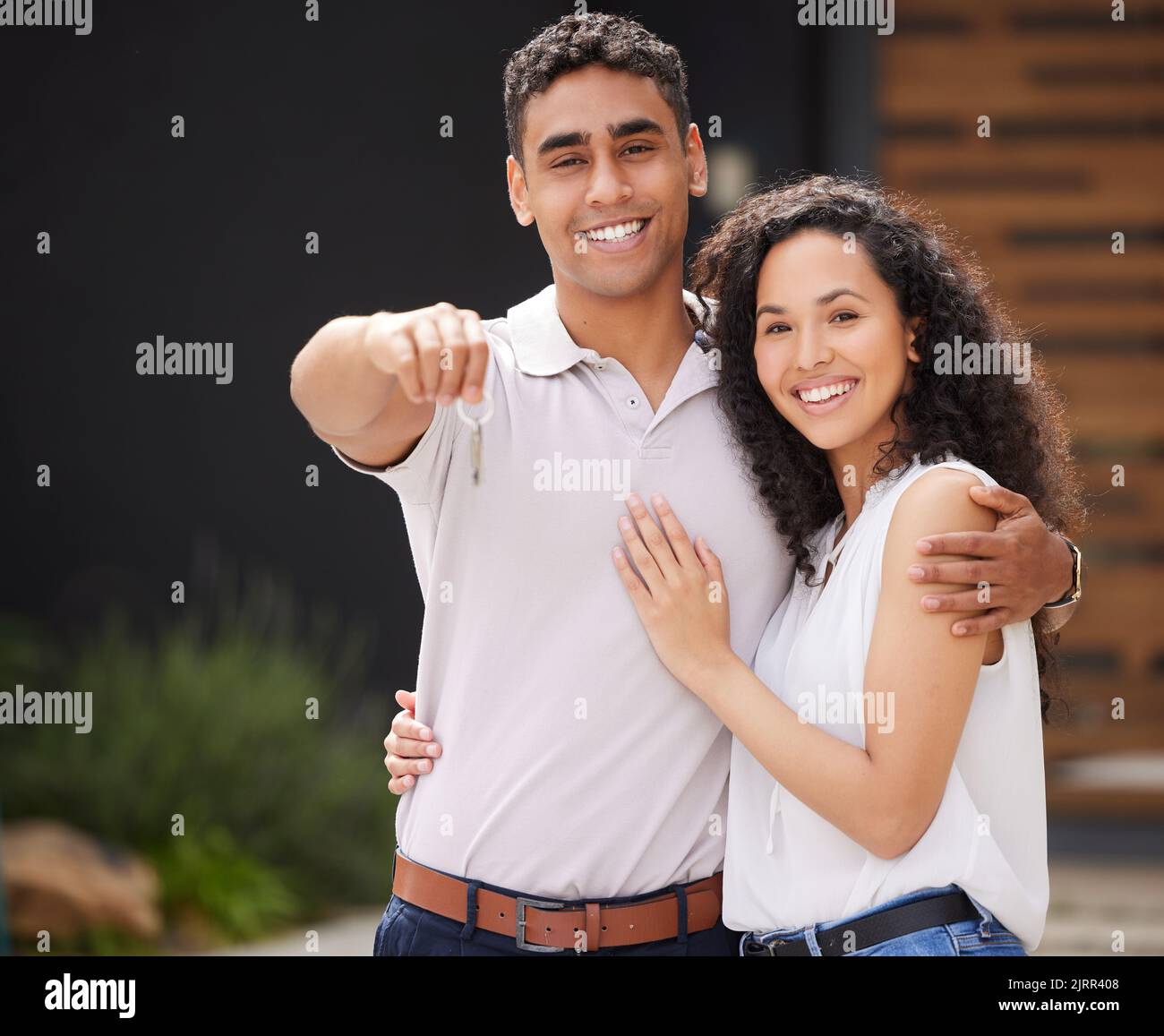 Glückliches Paar mit Schlüssel zum neuen Zuhause zusammen, Kauf von Immobilien als verheirateter Mann und Frau und Umzug in Immobilien-Haus. Porträt von Menschen, die umarmen Stockfoto