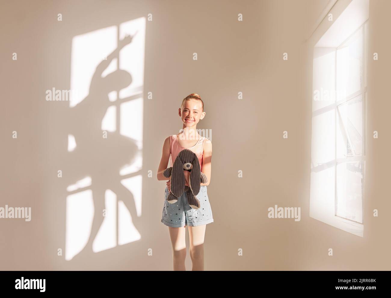 Kreative Kunst und Tanz mit einem Mädchen, das vom Ballett träumt, mit der Motivation und dem Ziel, Tänzerin in einem Studio mit einem Teddybären zu werden. Schatten einer Ballerina Stockfoto