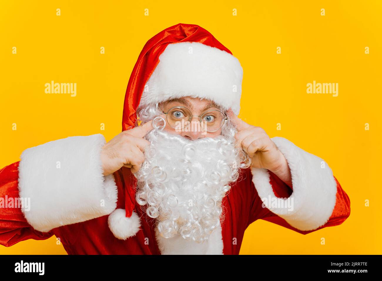 Der weihnachtsmann schaut auf die Kamera aus der Nähe auf einem gelben, isolierten Hintergrund Stockfoto