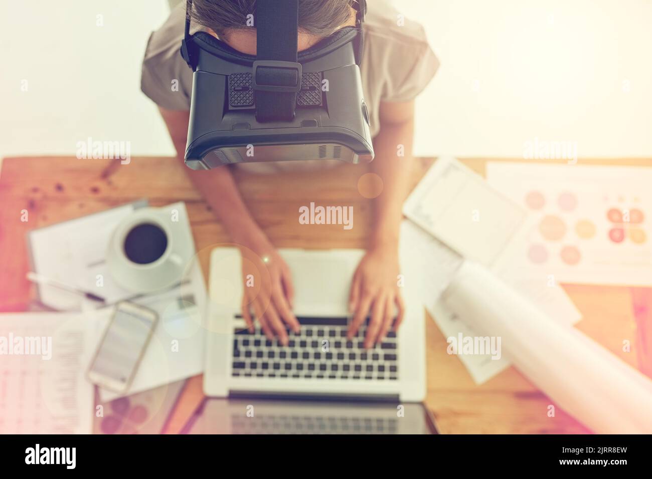 Der Umgang mit Geschäften in der virtuellen Welt. Aufnahme einer jungen Geschäftsfrau, die ein VR-Headset trägt, während sie in einem Büro arbeitet. Stockfoto