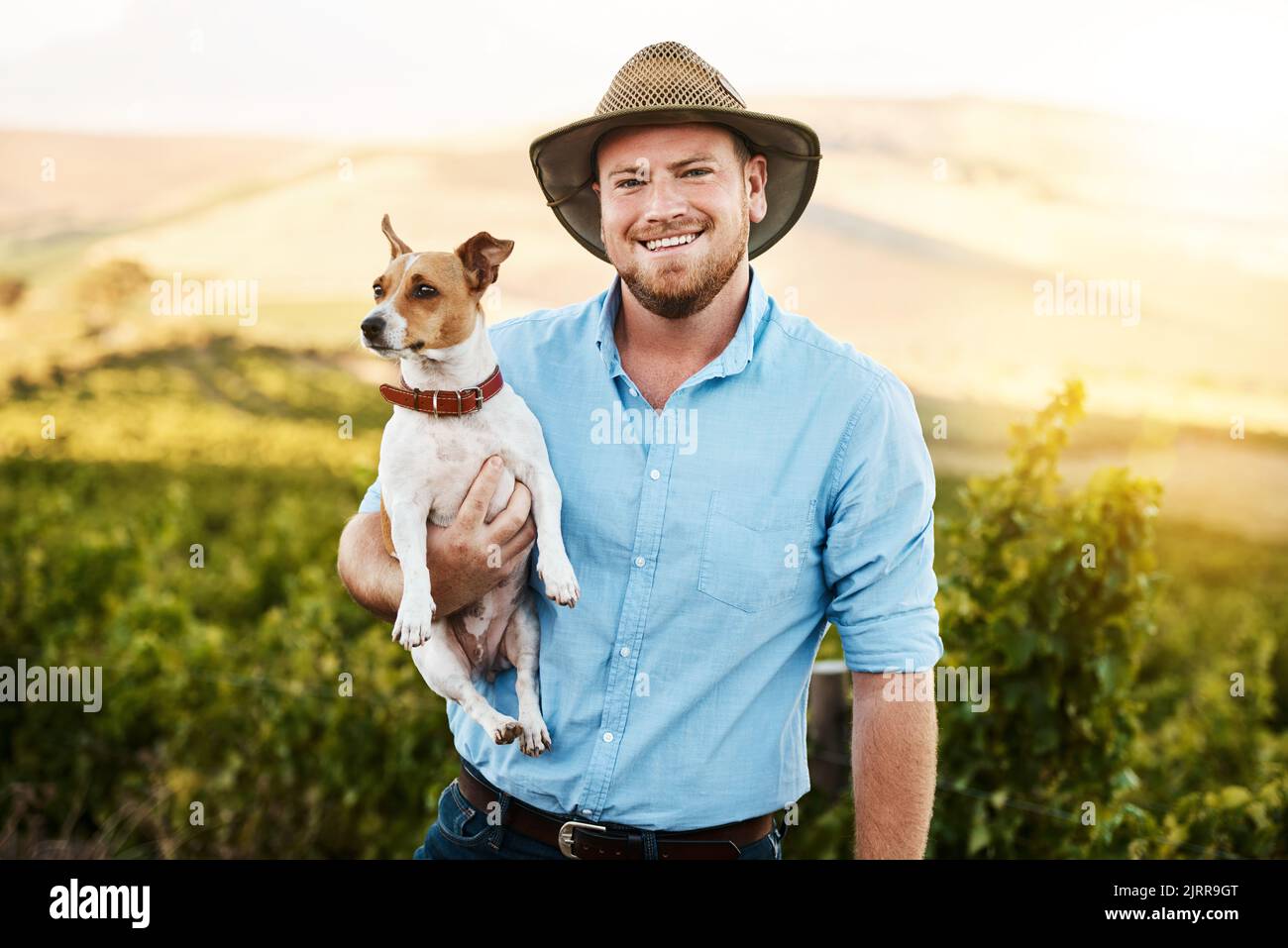 Wir beide arbeiten gerne zusammen auf dem Bauernhof. Porträt eines Bauern, der seinen Hund in einem Weinberg hält. Stockfoto