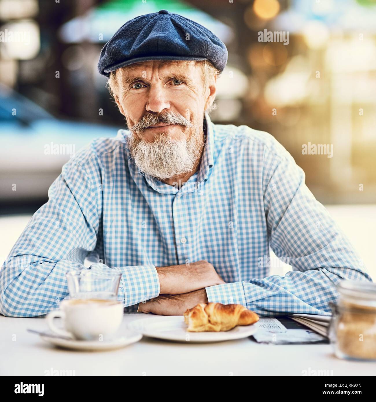 Meine Liebe zum Kaffee hat mich jung gehalten. Porträt eines glücklichen älteren Mannes, der eine Tasse Kaffee in einem Straßencafé genießt. Stockfoto