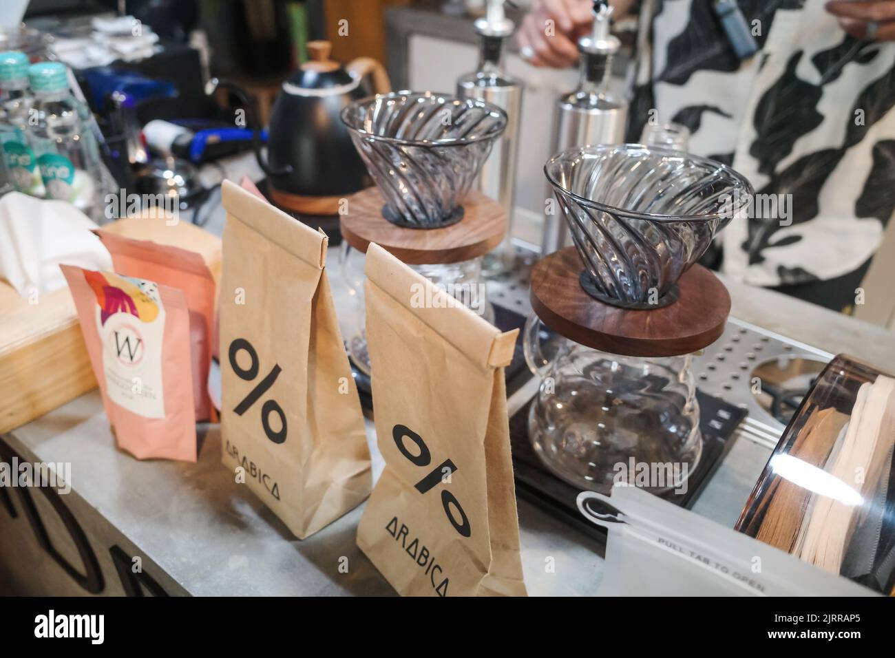 Kaffeezubereitungsausrüstung im lokalen Café mit Verkäufer im Hintergrund Stockfoto