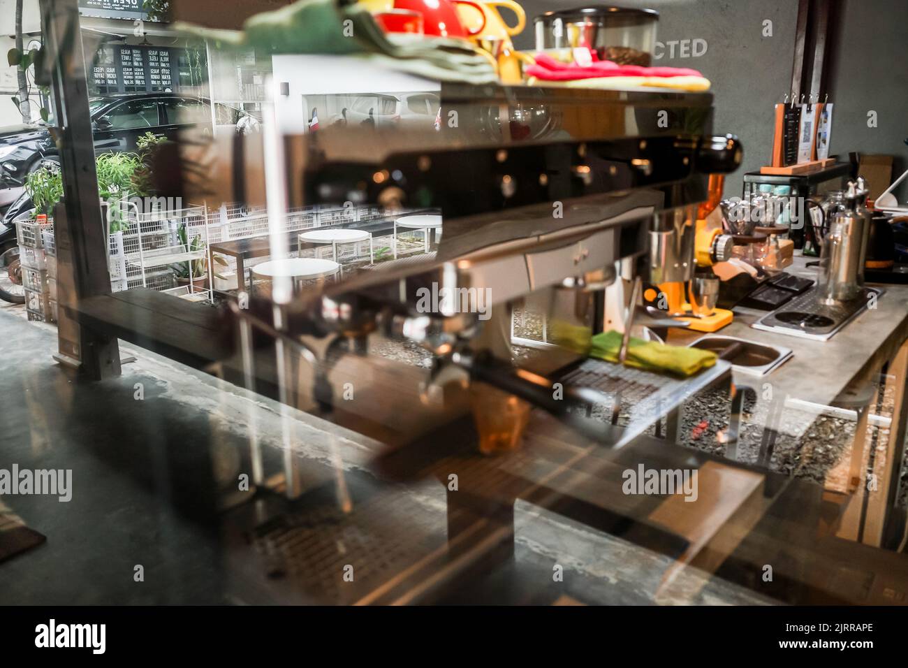 Ein Bild einer Kaffeemaschine in einem Coffee Shop, das von außerhalb des Fensters aufgenommen wurde und die Szene von außen reflektiert Stockfoto