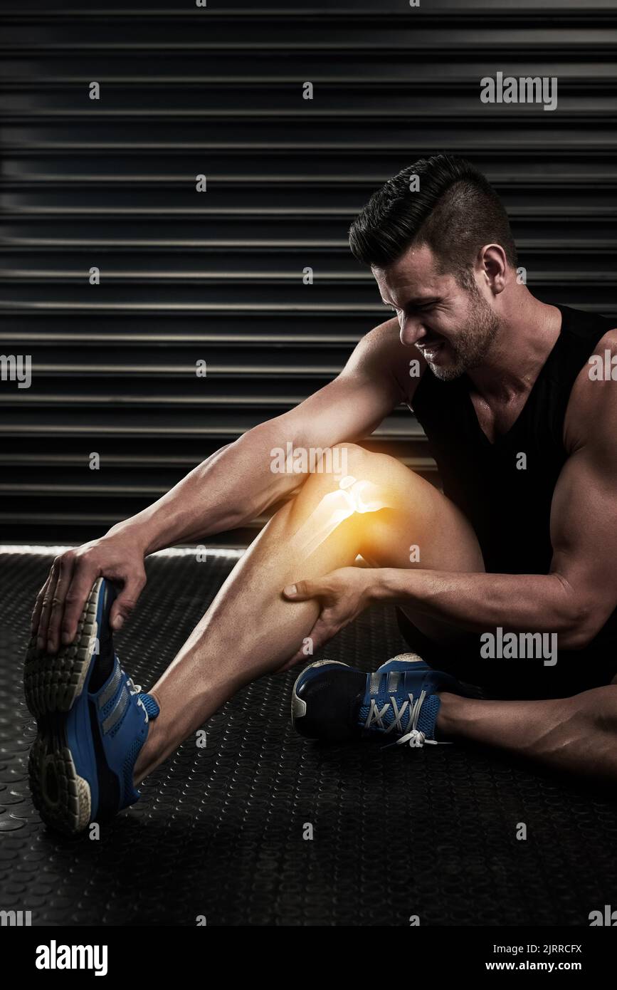 Eine Muskelverletzung zu überstehen. Studio-Aufnahme eines sportlichen jungen Mannes, der sich vor dem Training aufwärmt. Stockfoto