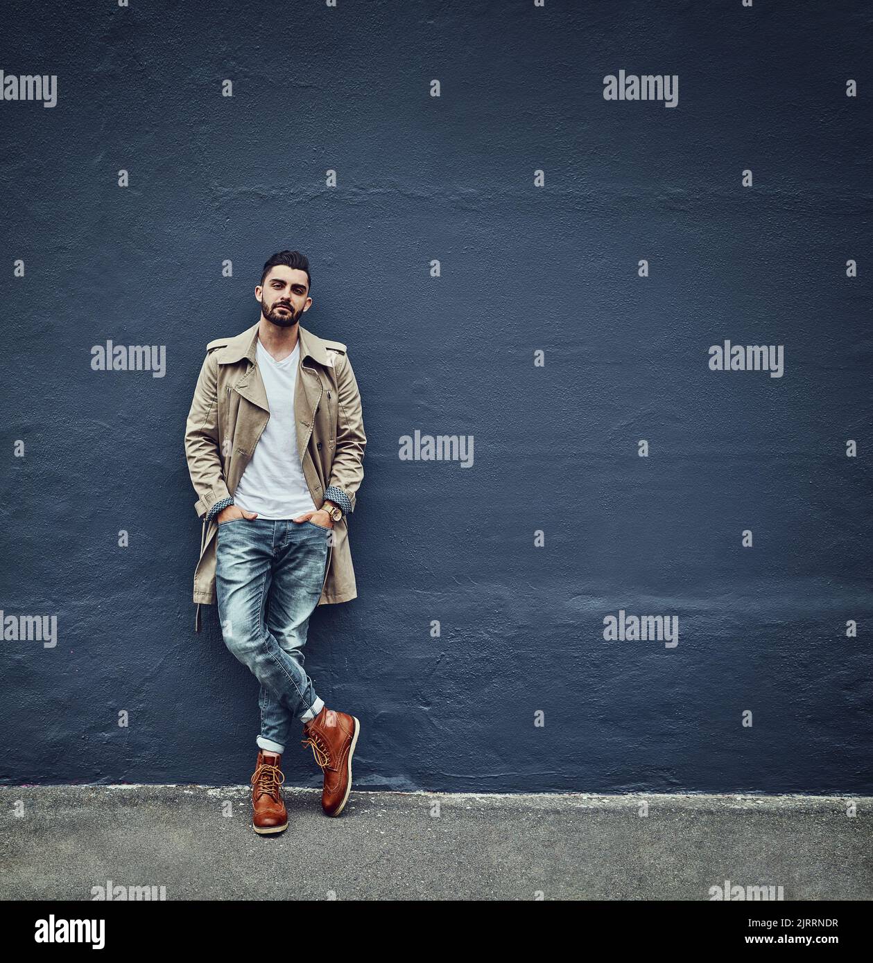 Streetwear richtig gemacht. Porträt eines modischen jungen Mannes in Stadtkleidung und posiert vor einer grauen Wand. Stockfoto