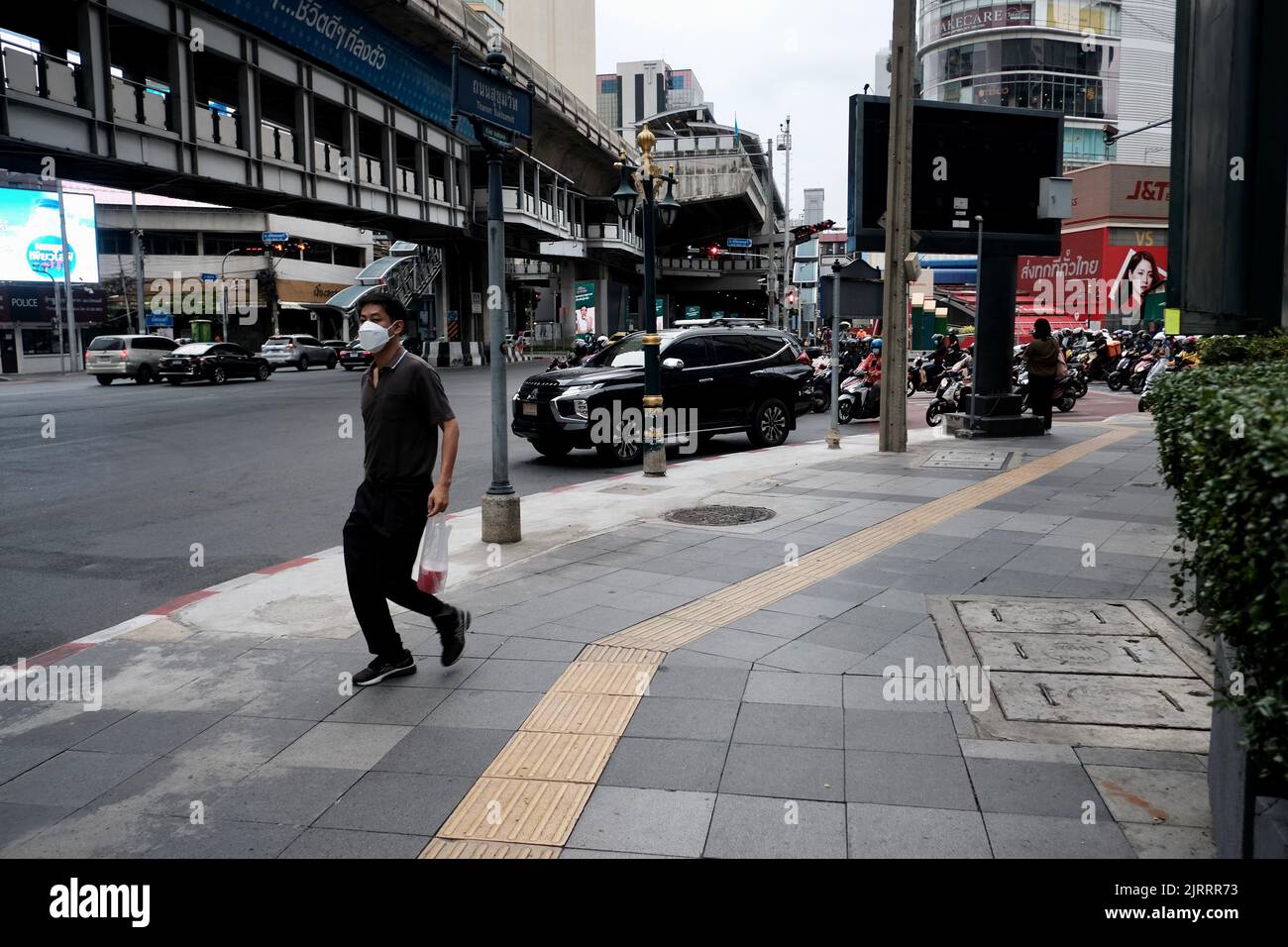 Mann, der die Soi Asoke aka Asok Montri Road aka Ratchadaphisek innere Ringstraße Bangkok Thailand hinunter läuft Stockfoto
