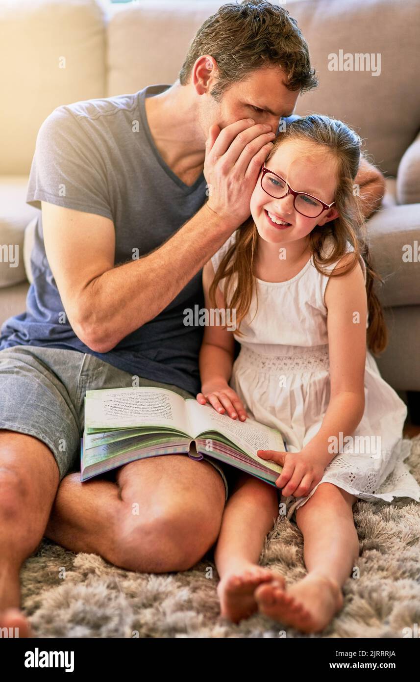 Es ist kein Geheimnis, wie sehr Papa seinen kleinen Engel liebt. Ein Vater flüstert zu Hause in seine kleinen Töchter. Stockfoto