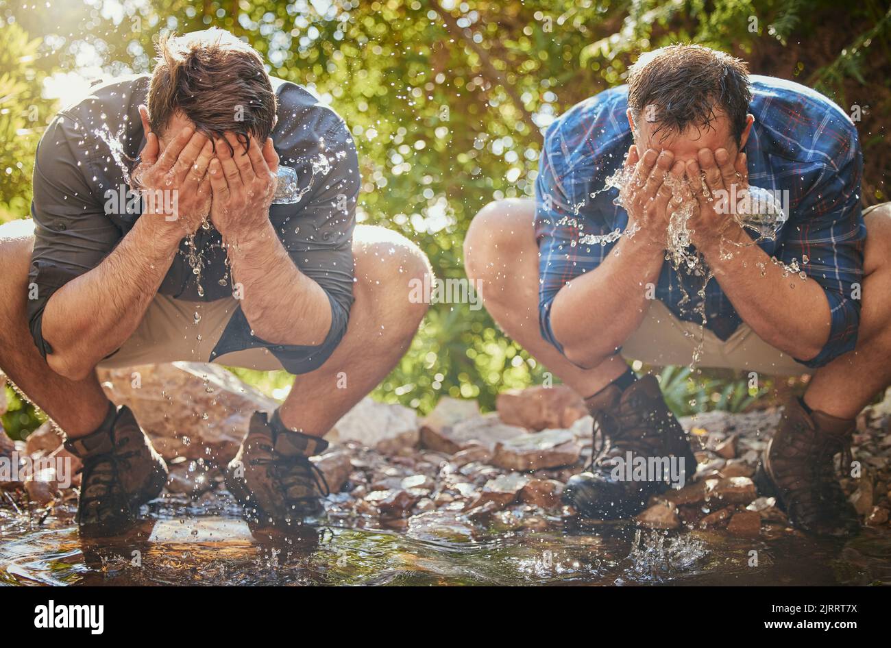 Wandermänner spritzen mit Wasser ins Gesicht, um sich zu kühlen, zu entspannen und Schmutz zu reinigen, wenn sie auf Felsen wandern oder im Wald wandern. Erde, Freiheit nach dem Campen Stockfoto