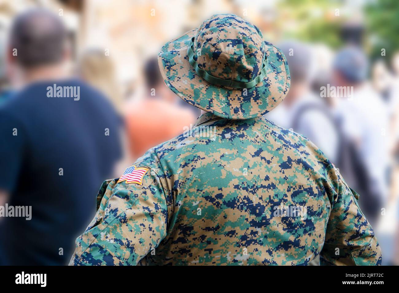 Amerikanischer Soldat Rückansicht Bewegung verwischen Hintergrund. Chevron mit der amerikanischen Flagge auf dem Ärmel einer grün verpixelten Militäruniform. Veterans Day Gedenktag. US Army die Streitkräfte der Vereinigten Staaten Stockfoto