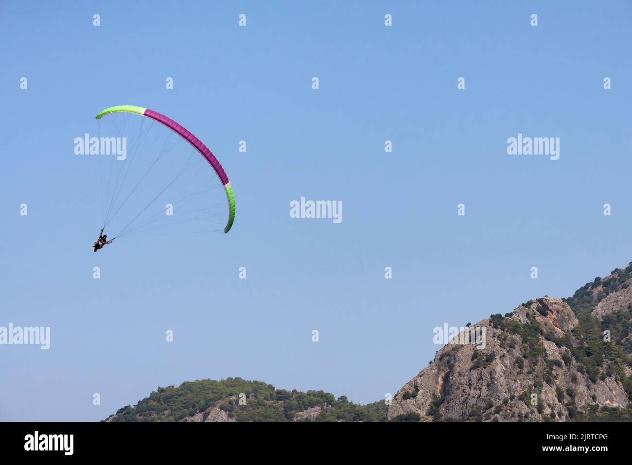 Touristisches Paragliding mit Pilot über die Berge Stockfoto
