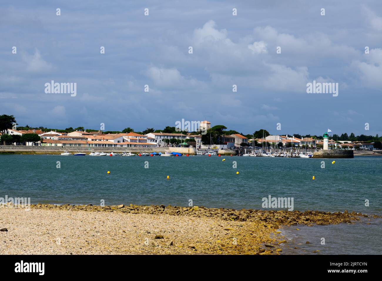 Blick auf die Phare de la Flotte und einige Boote auf dem Meer vom Strand Plage de l' Arnérault an einem sonnigen Sommertag mit der Stadt im Hintergrund Stockfoto