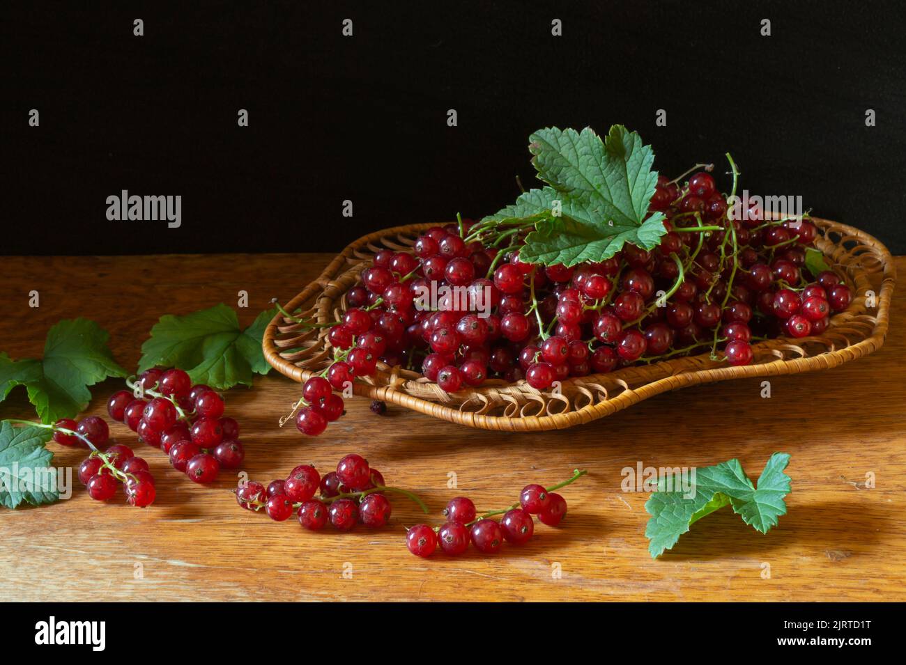 Rote Beeren auf einem Holztisch. Essen auf schwarzem Hintergrund.Saisonale Ernte im Sommer Stockfoto