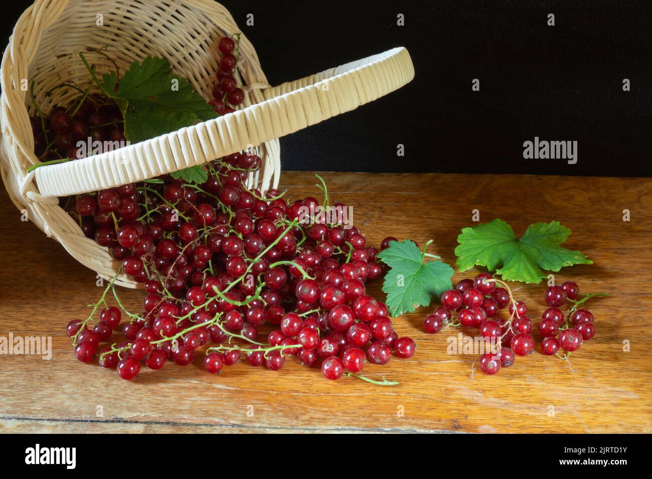 Rote Beeren auf einem Holztisch. Essen auf schwarzem Hintergrund.Saisonale Ernte im Sommer Stockfoto