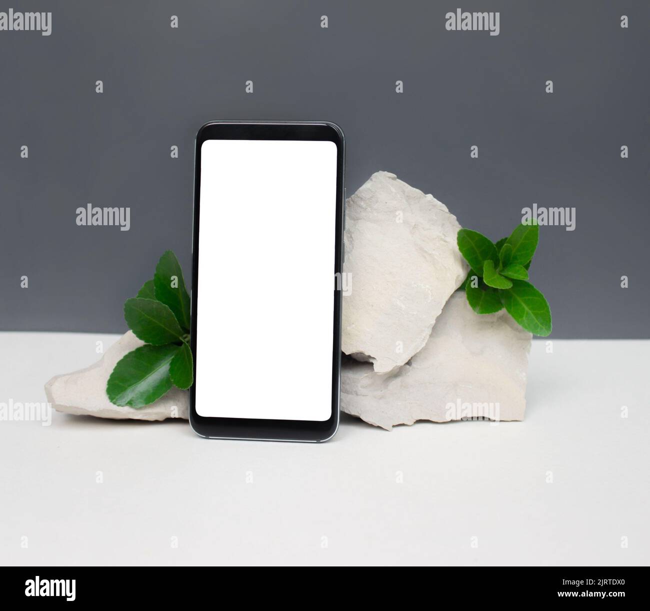 Mockup-Vorlage mit vertikalem Smartphone auf Natursteinen auf weiß-grauem Hintergrund.minimalistischer Stil Stockfoto