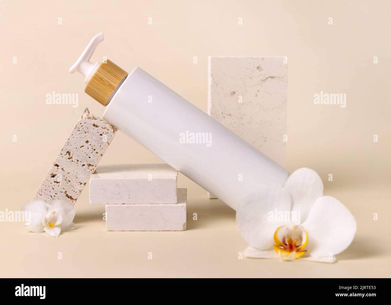Weiß nachfüllbar eine Pumpflasche in der Nähe von weißen Orchideenblüten und beigen Steinen auf hellbeige Nahaufnahme, kosmetisches Modell. Hautpflege Beauty-Produkt-Paket. Stockfoto