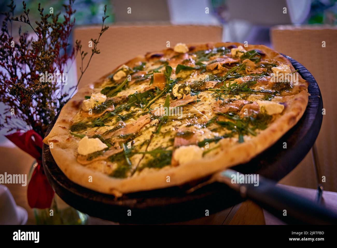 Leckere italienische Pizza mit Käse, Lachs und Rucola-Blättern. Nahaufnahme mit unscharfem Hintergrund Stockfoto