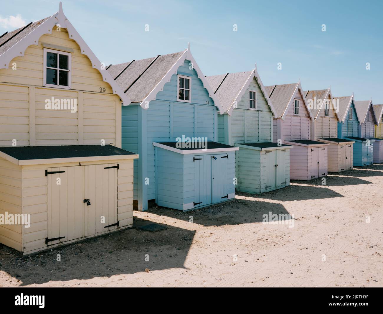 Die pastellfarbenen Sommerstrandhütten und der blaue Himmel am Strand in West Mersea, Mersea Island, Essex, England Stockfoto