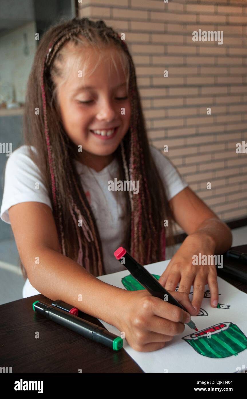 Ein glückliches kleines Mädchen zeichnet mit Markern. Stockfoto