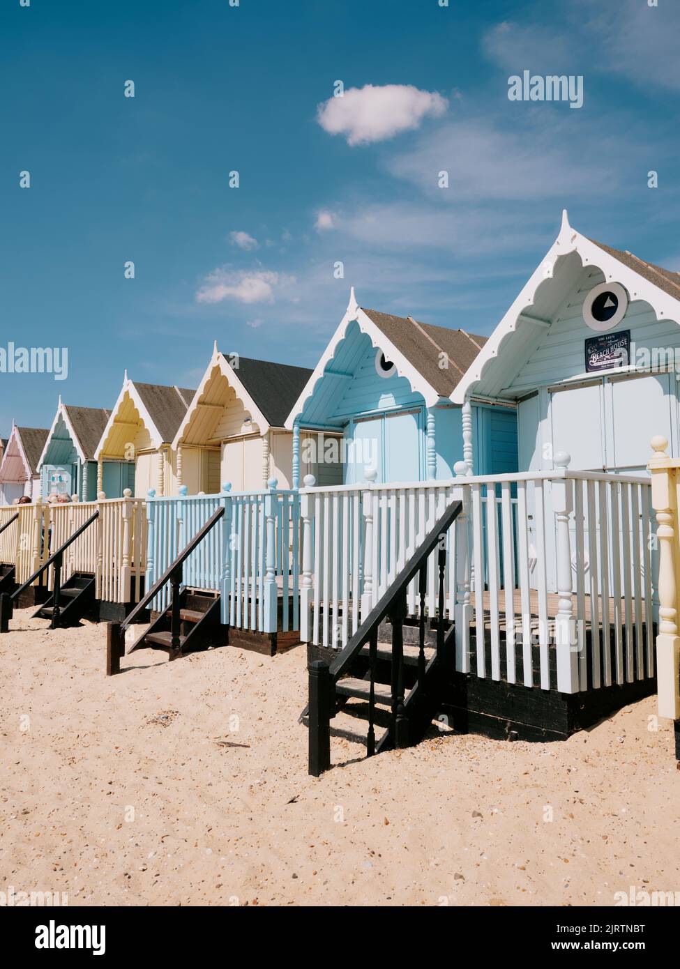 Die pastellfarbenen Sommerstrandhütten und der blaue Himmel am Strand in West Mersea, Mersea Island, Essex, England Stockfoto