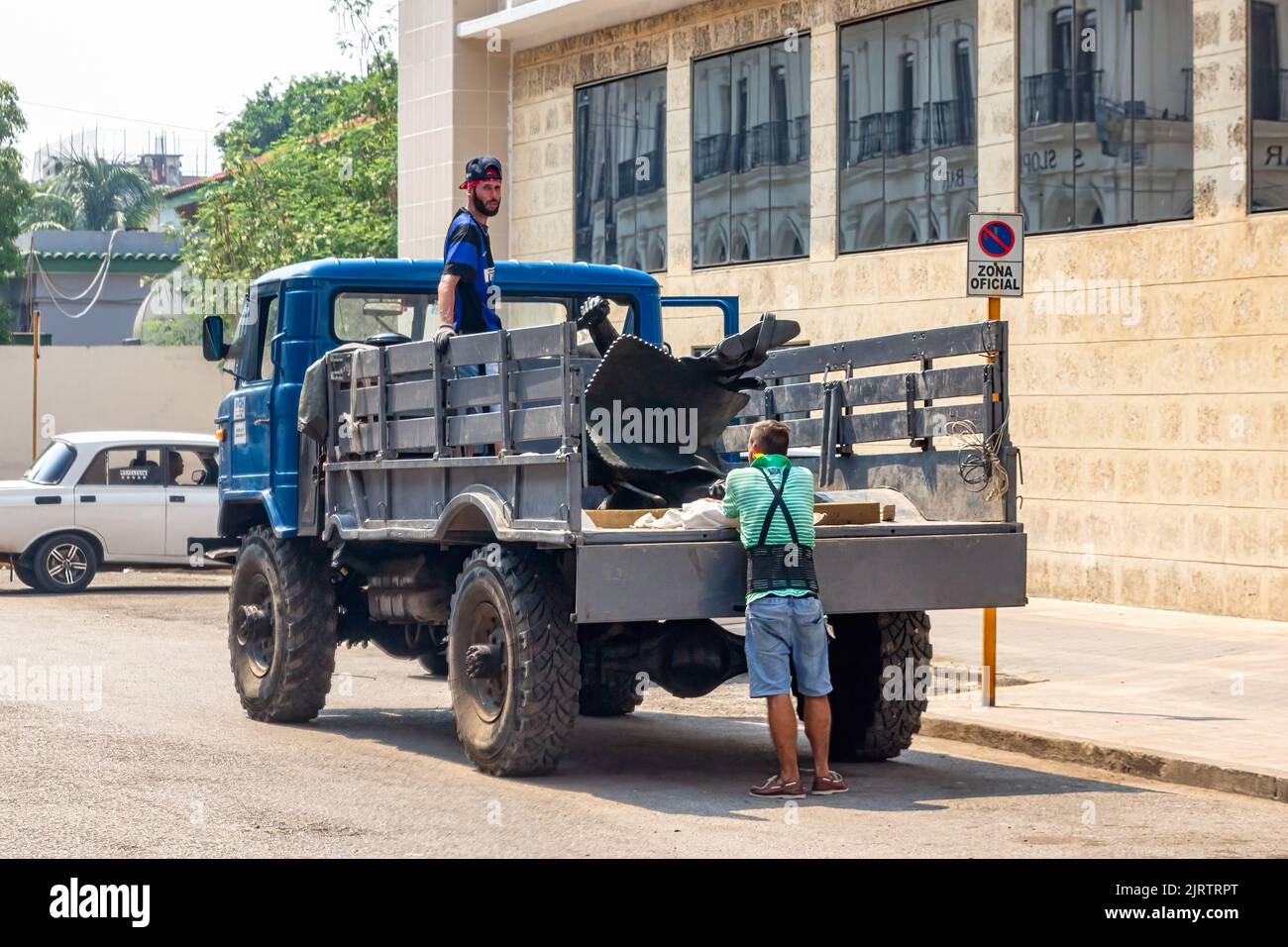 Kubanische Arbeiter auf der Rückseite eines veralteten russischen Lastwagens. Das Transportmittel wird in einer offiziellen Zone geparkt Stockfoto