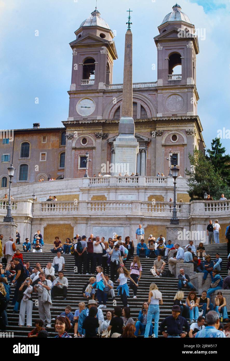 Rom Italien Besucher sitzen auf der Spanischen Treppe mit Trinita Dei Monti Kirche und Sallustiano Obelisk oben Stockfoto
