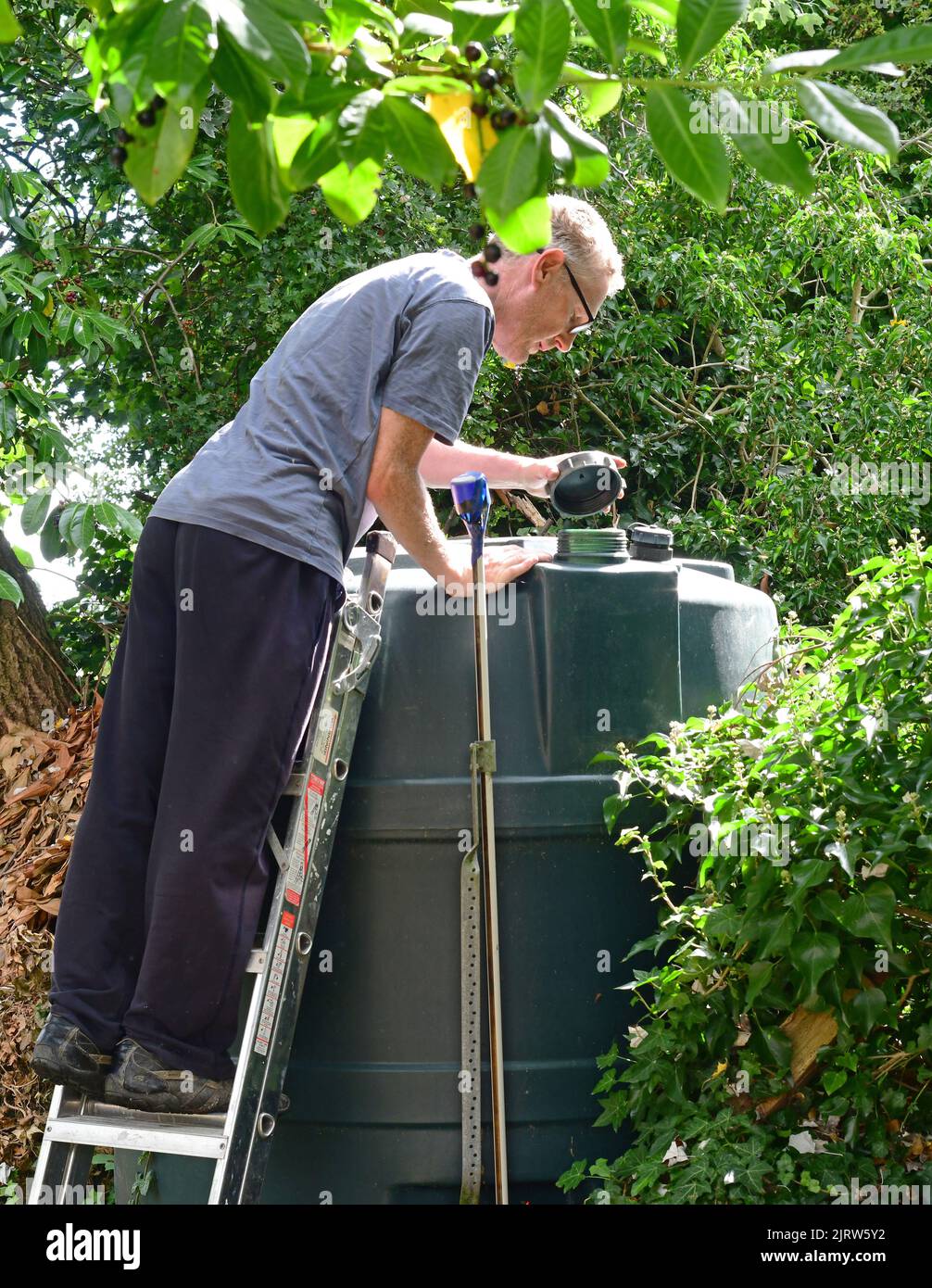 Mann, der den Füllstand des inländischen Heizöl-Tanks im Garten vereinigtes Königreich überprüft Stockfoto