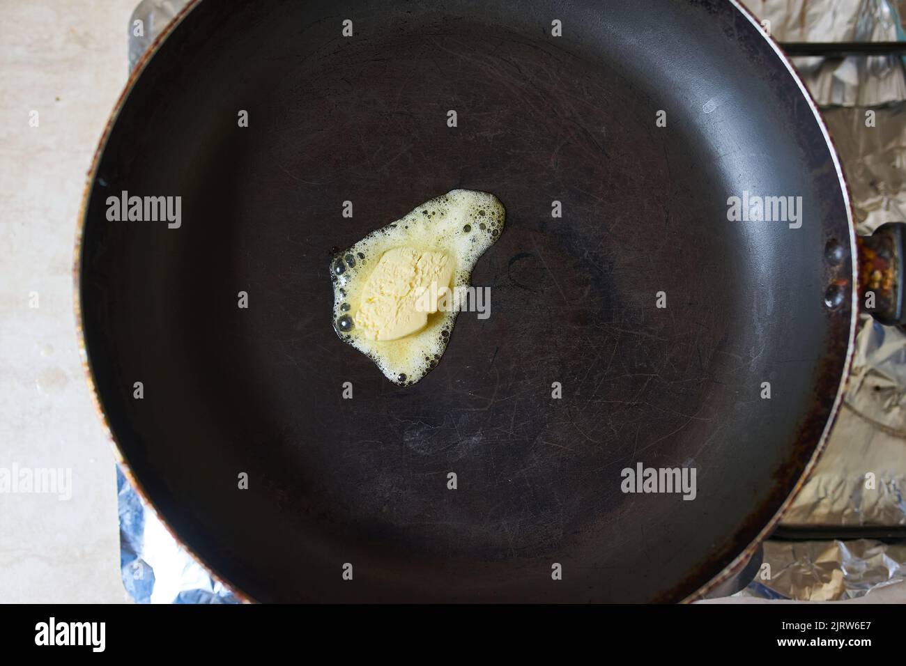 Eine Butter pat Schmelzen auf schwarzem Gusseisen Bratpfanne. Stockfoto