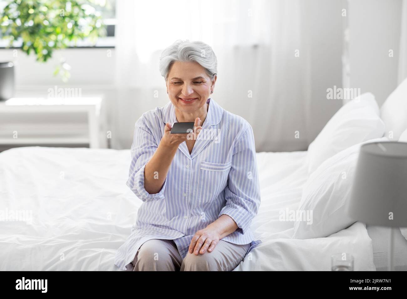Glückliche ältere Frau, die Stimme auf dem Smartphone aufzeichnet Stockfoto