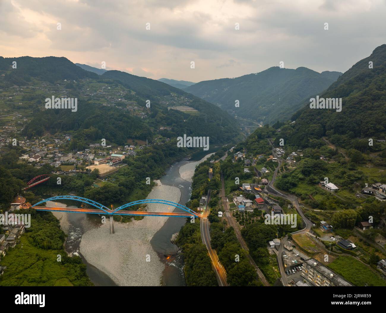 Luftaufnahme der blauen Brücke über den Fluss in der Berglandschaft in der Dämmerung Stockfoto