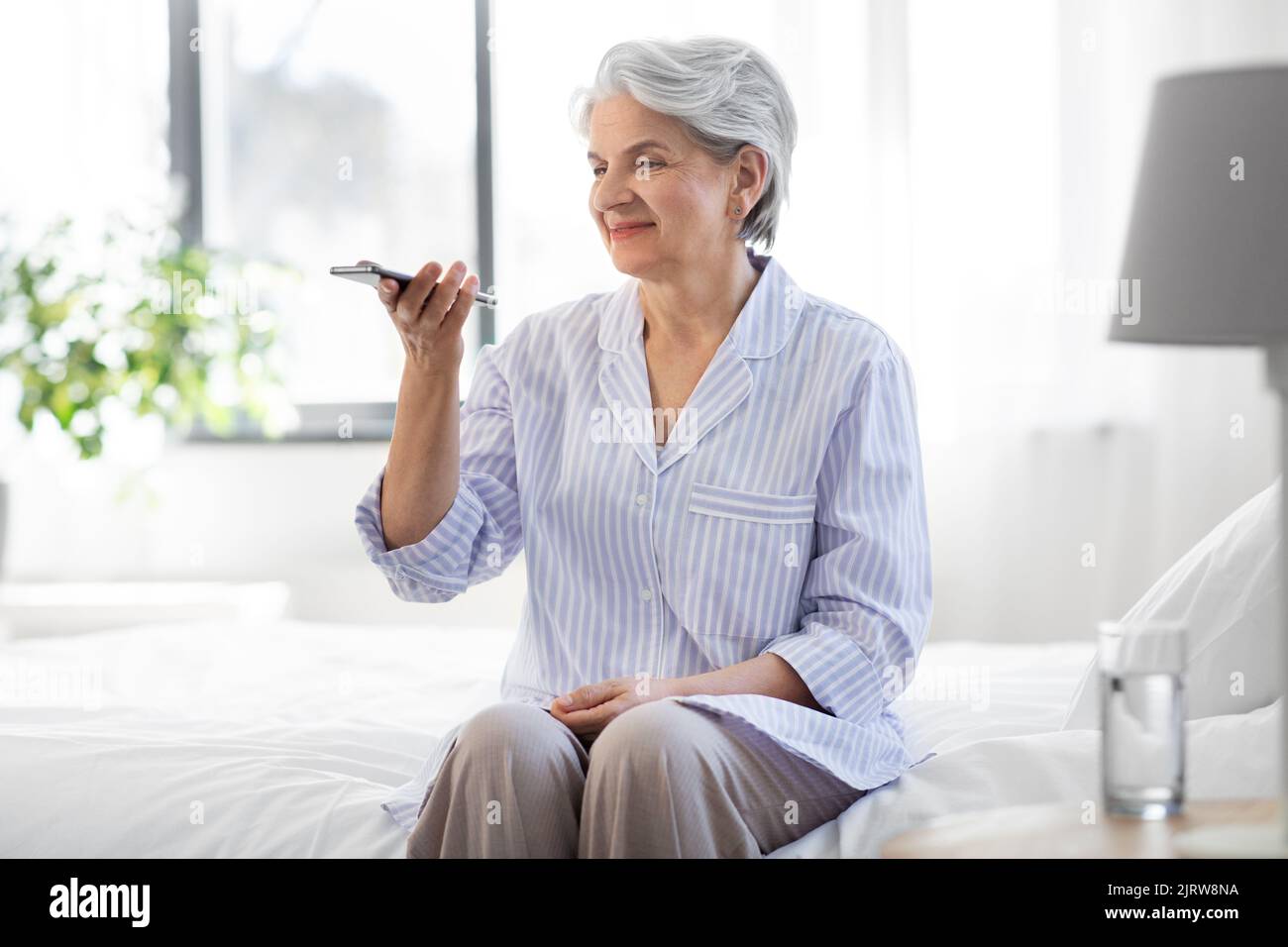Glückliche ältere Frau, die Stimme auf dem Smartphone aufzeichnet Stockfoto