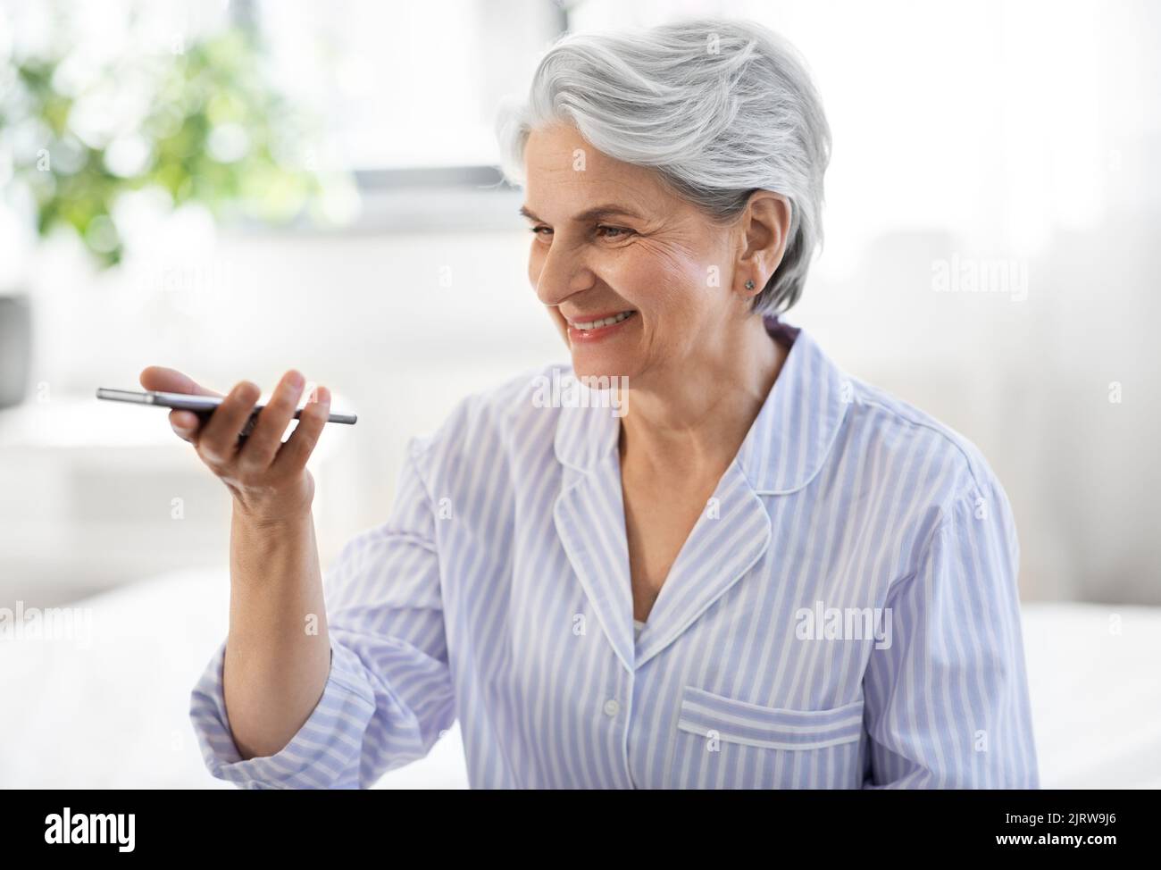 Glückliche ältere Frau, die Stimme auf dem Smartphone aufzeichnet Stockfoto