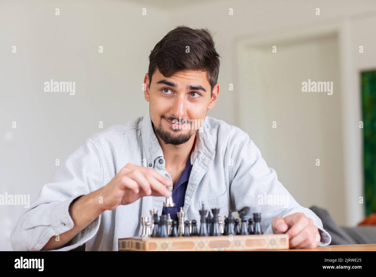 Junger Mann, der zu Hause Schach spielt Stockfoto