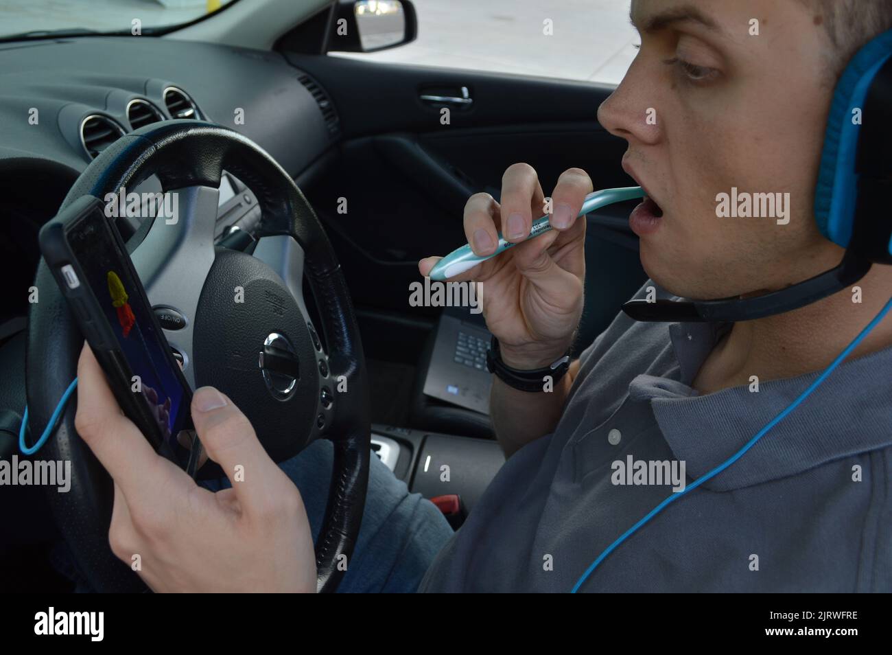 Abgelenkt fahren, Zähneputzen und Telefonieren während der Fahrt Stockfoto