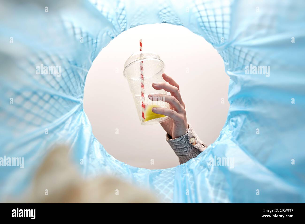 Die Hand wirft Plastikbecher in den Mülleimer Stockfoto