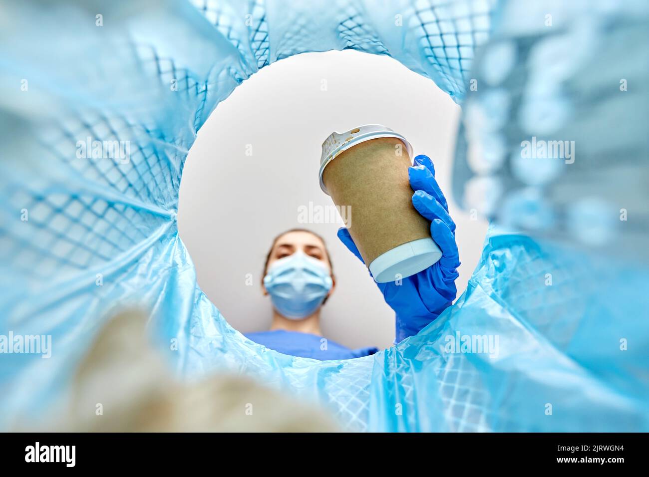 Ärztin wirft Kaffeetasse in den Mülleimer Stockfoto