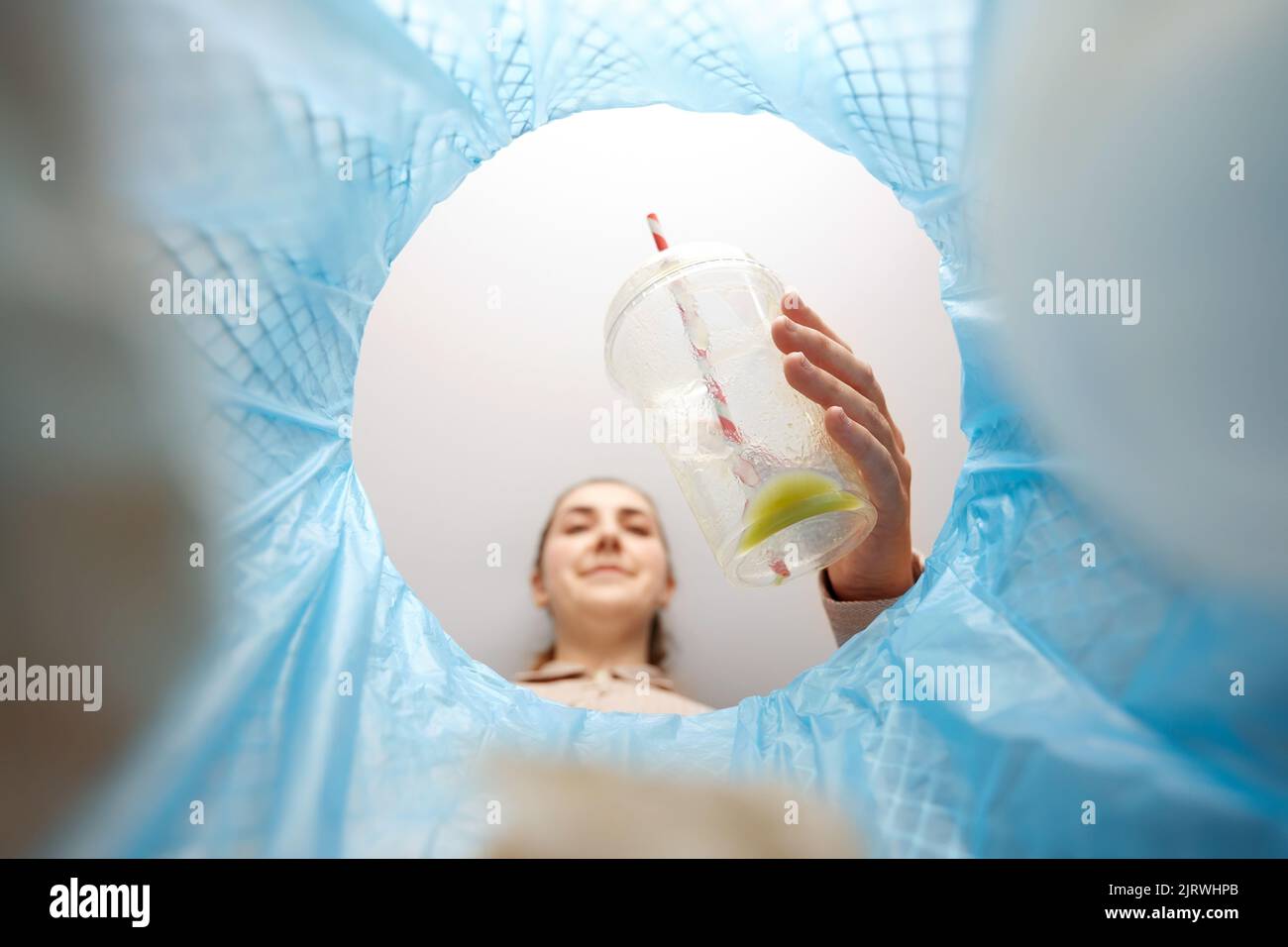 Frau wirft Plastikbecher in den Mülleimer Stockfoto