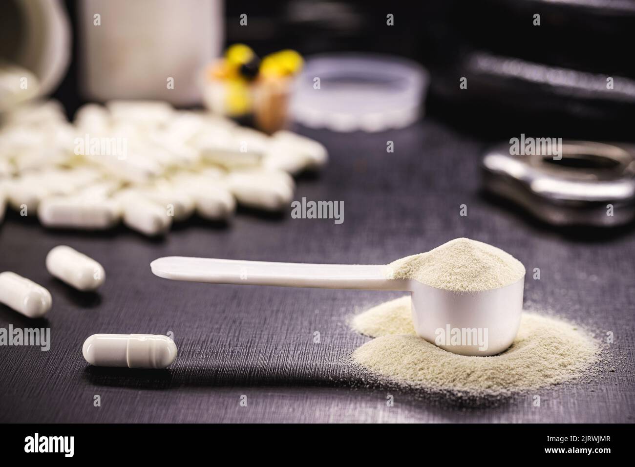Messlöffel mit Kreatin oder Molke und Steroidtabletten, Nahrungsergänzungsmittel, Kasein-Cocktail, Muskelmasse-Vitamin, Überzocktes Karosseriekonzept Stockfoto