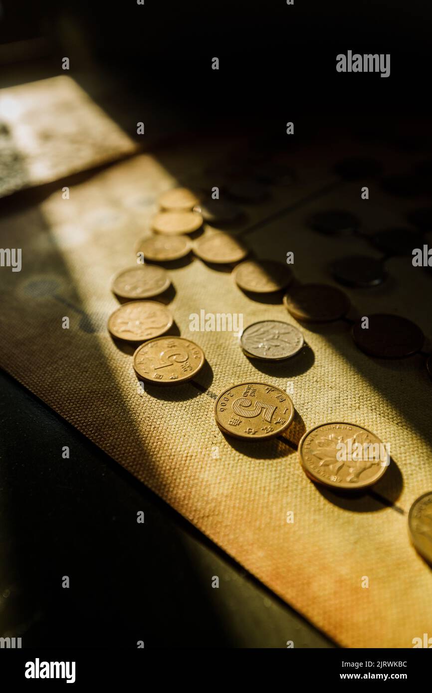 Ein vertikales Bild chinesischer Münzen auf altem, strukturiertem Papier, das dem Sonnenlicht ausgesetzt ist Stockfoto