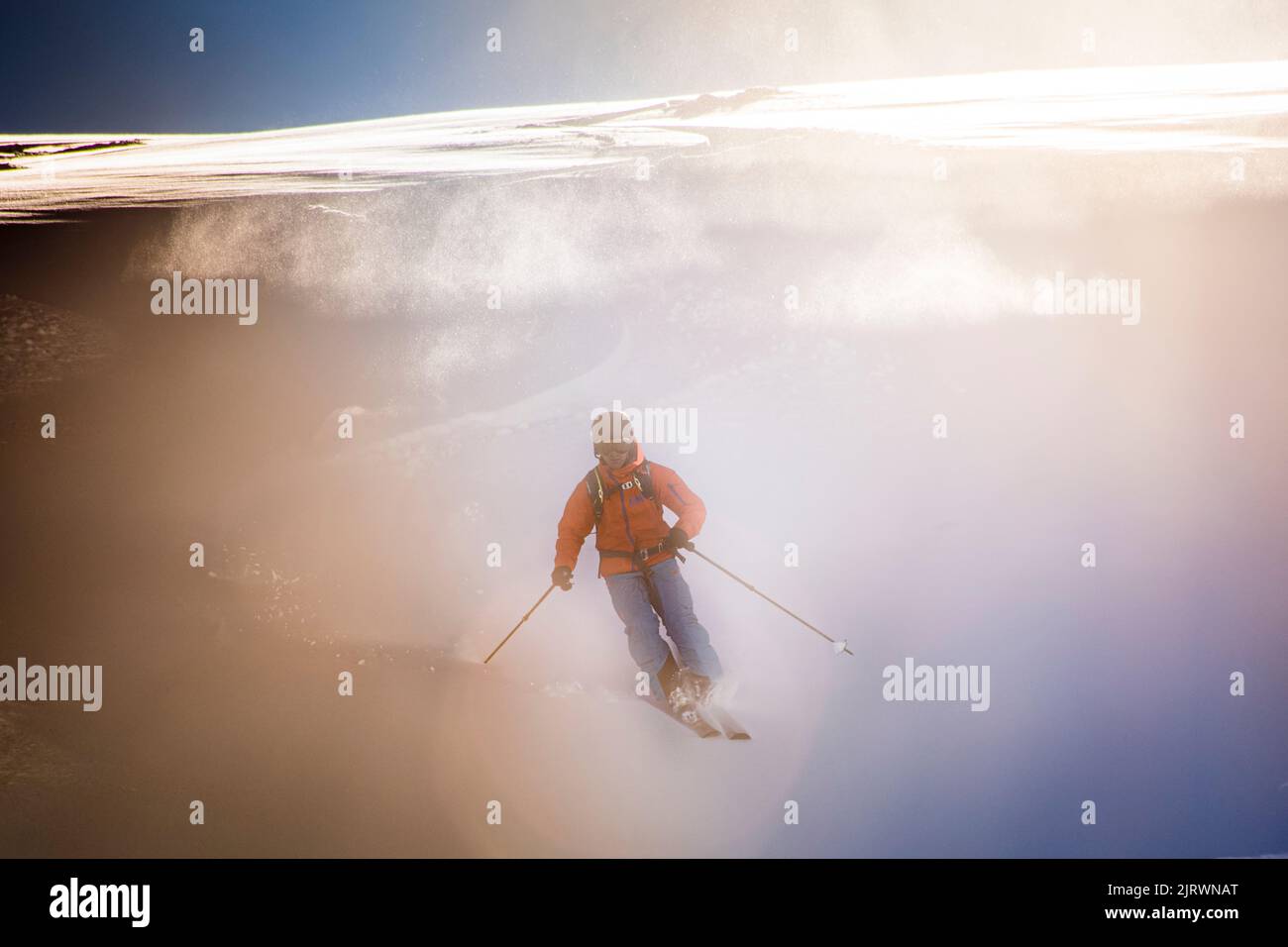 Single Off Piste Skifahrer steigt frischen Pulverschnee Piste mit Sonne hinter Stockfoto