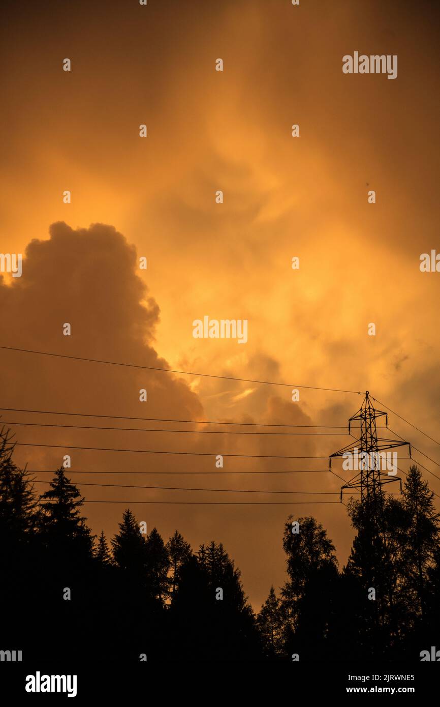 Goldenes Licht in einem bewölkten Himmel nach einem Sturm. Strommasten werden gegen die dramatischen Wolken geschildet. Stockfoto