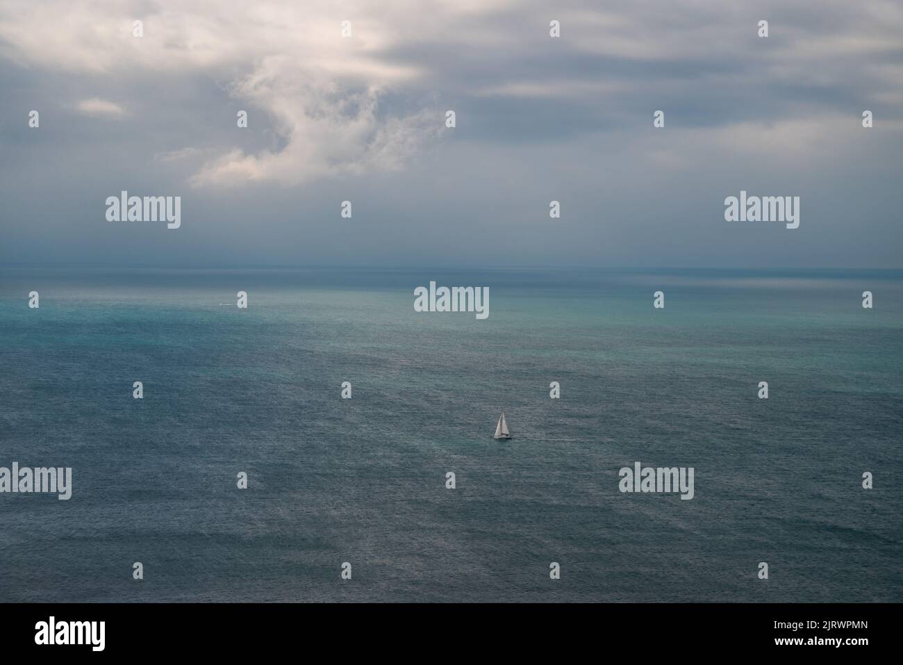 Dramatische Meereslandschaft mit stürmischem Himmel und kleinem weißen Segelschiff, Dorset, Großbritannien Stockfoto