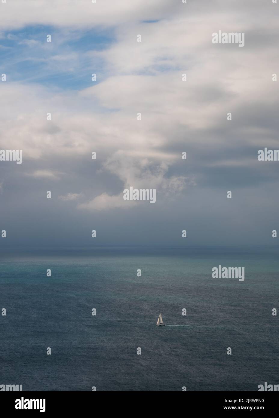 Dramatische Meereslandschaft mit stürmischem Himmel und kleinem weißen Segelschiff, Dorset, Großbritannien Stockfoto