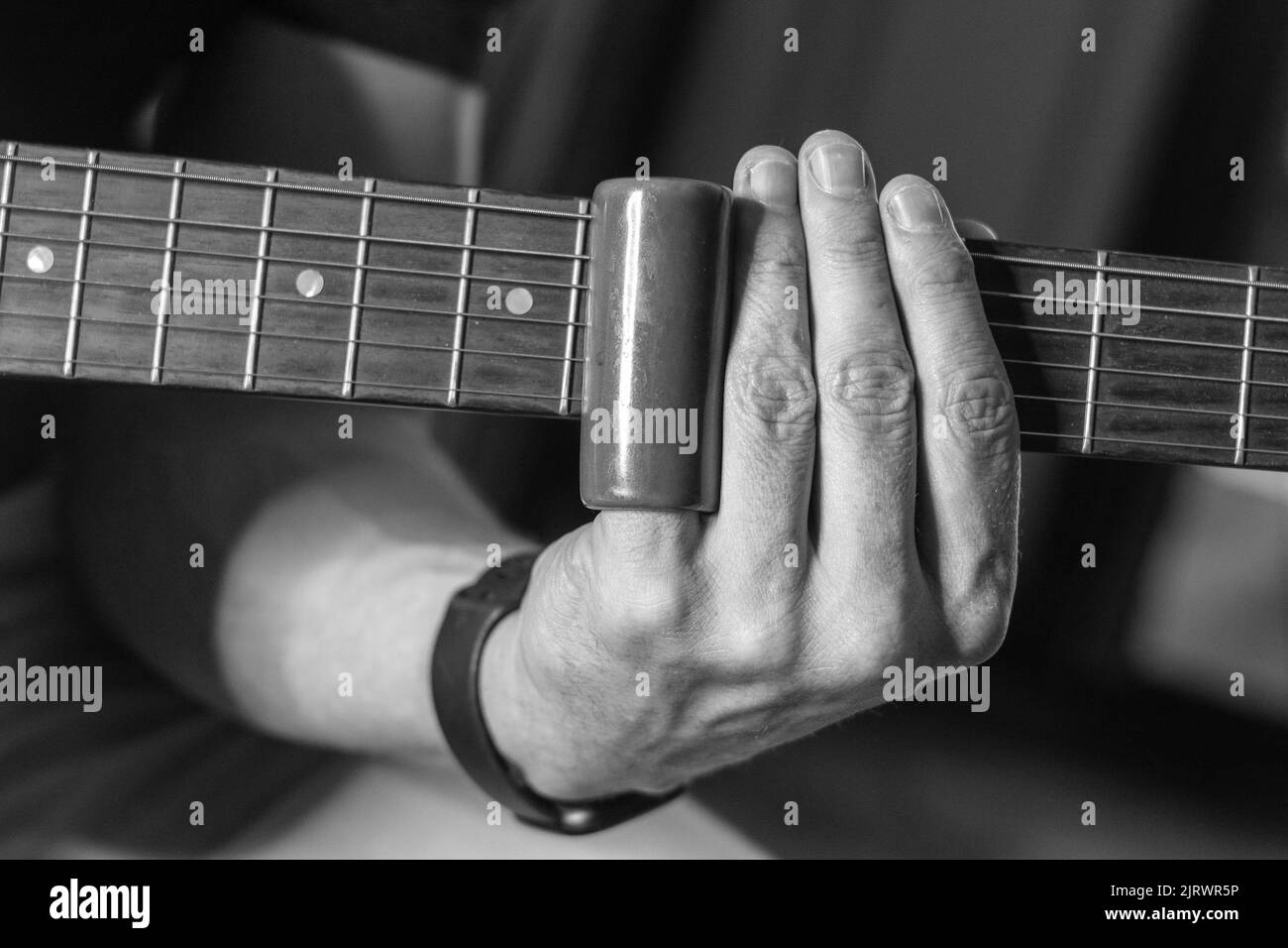 Eine Nahaufnahme eines E-Gitarristen, der mit Slider-Technik, Graustufen, auftrat Stockfoto