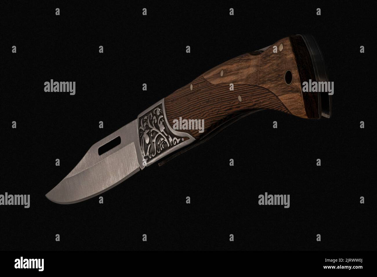 Nahaufnahme eines faltbaren handgefertigten Messers mit scharfer Klinge, Holzgriff auf schwarzem Hintergrund hergestellt in Kambodscha Stockfoto