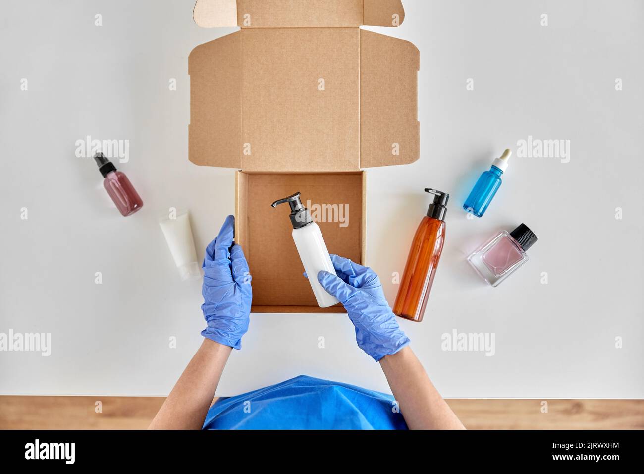 Hände in Handschuhen Verpackung Paket Box mit Kosmetik Stockfoto